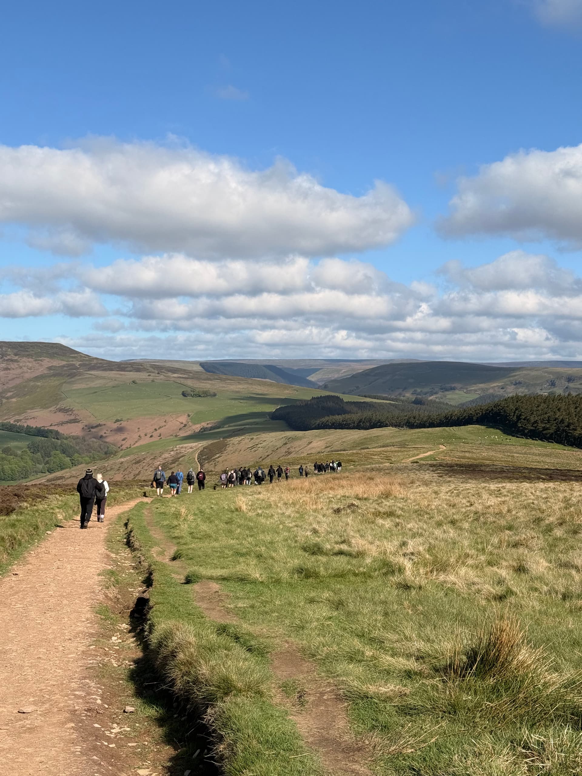 Group walking along the Win Hill ridge under dramatic skies